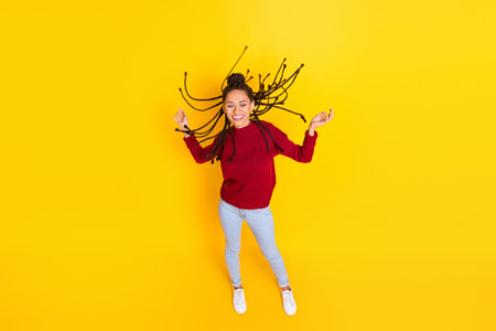 Full length photo of charming sweet dark skin lady wear red pullover smiling dancing isolated yellow color backgroundの写真素材