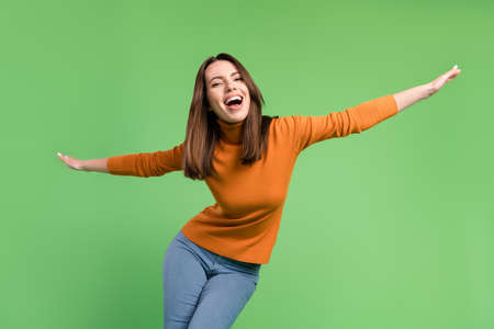 Portrait of attractive cheerful funny girl having fun dancing like plane clubbing isolated over green color backgroundの写真素材