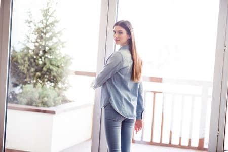 Photo of charming pretty young happy woman window morning wear denim shirt indoors inside house homeの写真素材