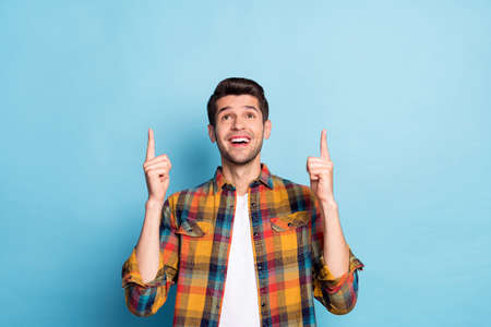 Portrait of attractive cheerful guy demonstrating up copy blank place space ad isolated over bright...