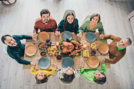 Top above high angle view portrait of adorable cheerful family holding hands eating homemade dish at home indoorsの写真素材