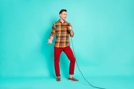 Full length photo of funny brunet millennial guy talk in mic wear shirt trousers sneakers isolated...