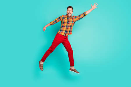Full length photo of cool brunet millennial guy jump wear shirt trousers sneakers isolated on teal backgroundの写真素材