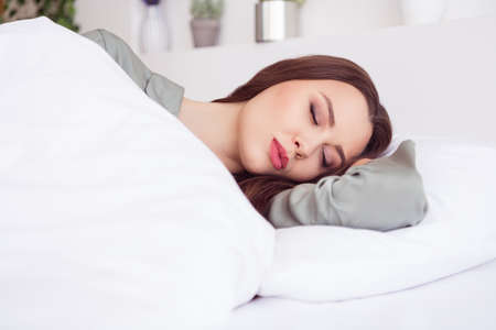 Portrait of attractive calm girl lying in bed sleeping sweet dream at home house light white interiorの写真素材