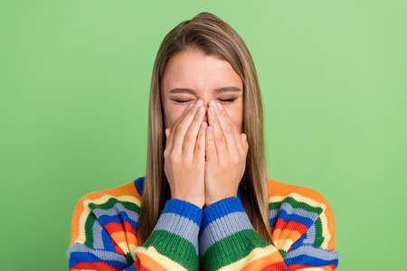 Photo portrait girl laughing shut face with hands closed eyes striped sweater isolated pastel green...