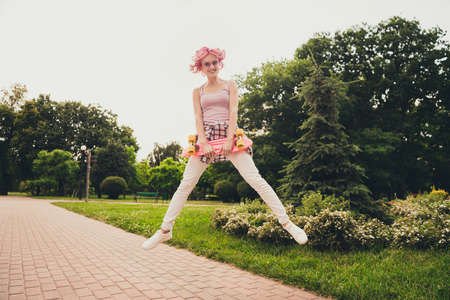 Full length body size view of attractive cheerful girl jumping spending vacation holding skate on...