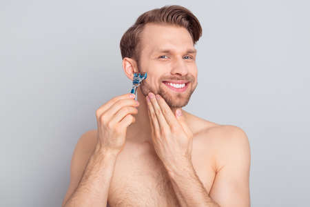 Photo of funny cheerful blond hair young guy no clothes smiling shaving cheekbones cheeks isolated grey color backgroundの写真素材