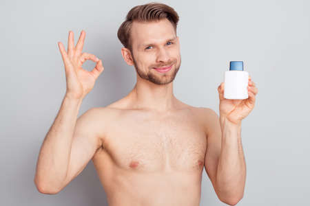 Photo of recommend young blond man hold bottle show okey sign without clothes isolated on grey color backgroundの写真素材