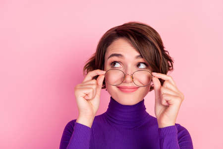 Photo of curious brunette young lady hold spectacles look empty space wear violet turtleneck...