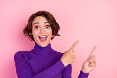 Photo of cool brunette young lady point empty space wear violet jumper isolated on pink color backgroundの写真素材