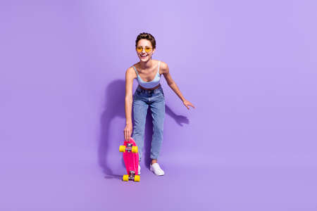 Full length body size view of lovely cheerful girl skating having fun hobby isolated over bright purple violet color backgroundの写真素材