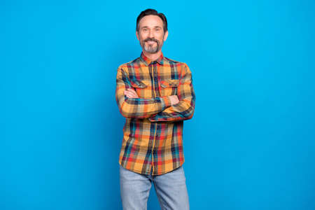 Photo portrait business man with folded hands smiling happy wearing checkered shirt blue jeans isolated vivid blue color backgroundの写真素材