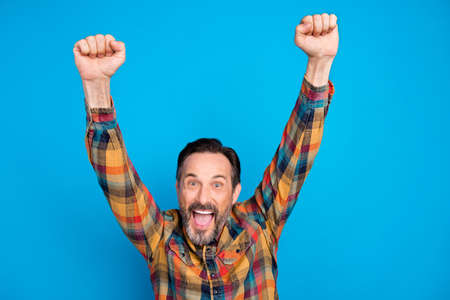 Photo of hooray brunet hairdo age man hands up wear yellow shirt isolated on blue color backgroundの写真素材