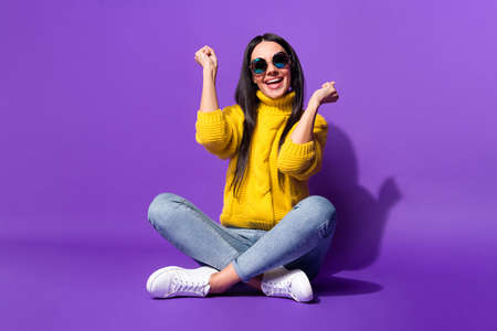 Full size portrait of astonished lady sit fists up open mouth smile yeah isolated on purple color...
