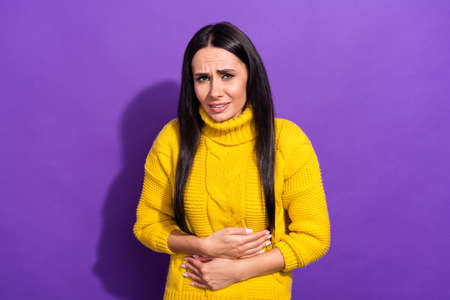 Photo of unsatisfied attractive person arms on stomach feeling bad isolated on violet color...