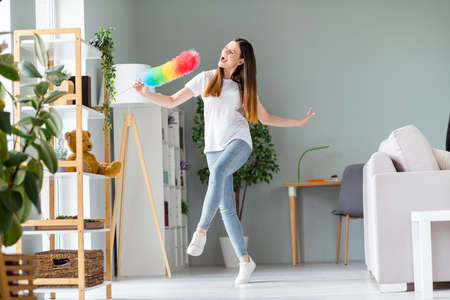 Full length body size view of attractive cheerful childish girl dancing singing in fluffy brush fooling vacation at home indoorsの写真素材