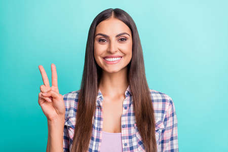 Photo of sweet millennial brunette lady show v-sign wear purple shirt isolated on cyan color...