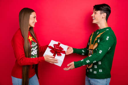 Photo of best friends exchange gifts celebrate x-mas party wear ugly pullover isolated red color backgroundの写真素材