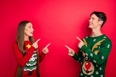 Photo of interested two friends indicate finger empty space wear ugly pullover isolated red color backgroundの写真素材