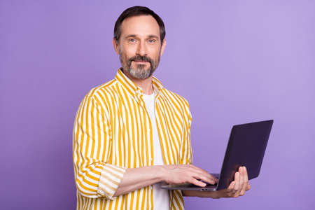 Photo of charming confident age gentleman wear yellow shirt smiling typing modern device isolated...