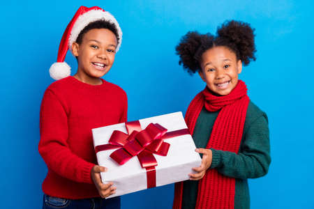 Photo of funky shiny dark skin children wear pullover headwear scarf giving present isolated blue color background
