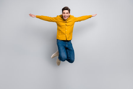 Full length body size view of attractive free cheery man jumping flying wings isolated over grey...