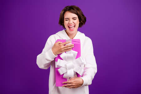 Photo of good mood positive screaming girl hug embrace birthday present excited isolated on purple color backgroundの写真素材