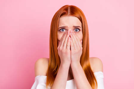 Portrait of attractive desperate worried red-haired girl closing mouth oops hide fear isolated over...