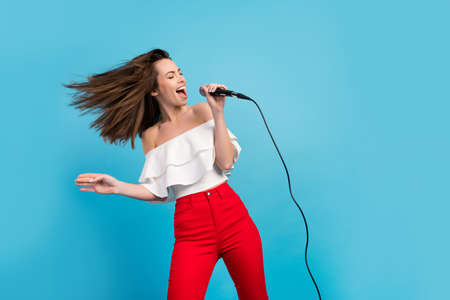 Photo of cool brunette millennial lady sing wear blouse jeans isolated on blue color backgroundの写真素材