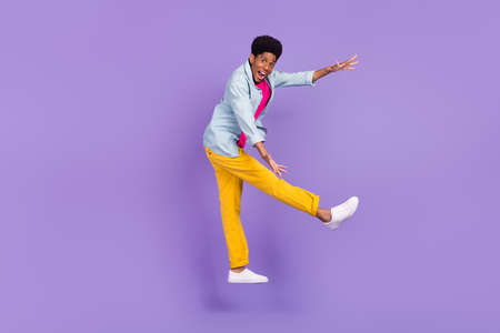 Photo of promoter guy jump arms hold empty space wear blue shirt pants shoes isolated purple color backgroundの写真素材