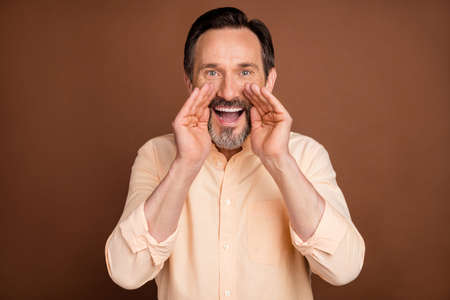 Photo of mature brunet man hands yell wear peach shirt isolated on brown color background