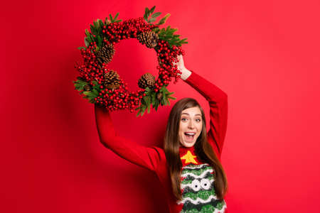 Photo of cool young lady hold door decoration wear holiday sweater isolated on red color backgroundの写真素材
