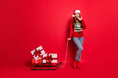 Full length photo of impressed millennial lady take sledge wear sweater cap jeans boots isolated on red color backgroundの写真素材