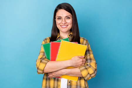 Portrait of attractive intelligent cheerful girl holding book studying isolated over vibrant blue color backgroundの写真素材