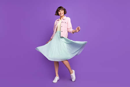 Full size photo of young happy pretty woman good mood wear fly skirt wind blow isolated on violet color backgroundの写真素材