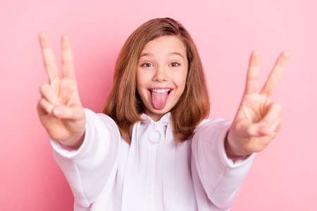 Portrait of attractive cheerful girl showing double v-sign grimacing having fun isolated over pink...