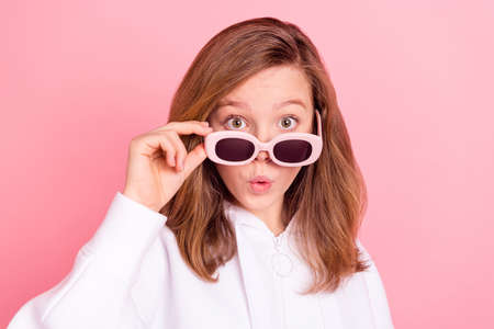Portrait of attractive amazed cheerful girl touching specs sudden news reaction isolated over pink...