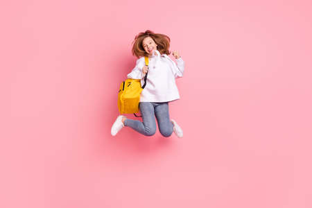 Full length body size girl jumping up wearing yellow rucksack gesturing like winner isolated pastel pink color backgroundの写真素材