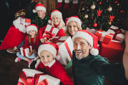 Photo portrait of big full family wearing red cap smiling together xmas spirit keeping presents dad taking selfieの写真素材