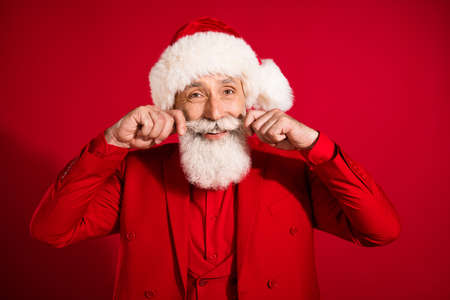 Photo of handsome pretty mature man dressed christmas costume hat arms mustaches isolated red color backgroundの写真素材