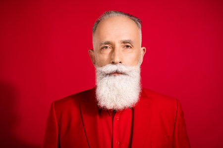 Photo of strict grey old man wear red suit isolated on red color backgroundの写真素材