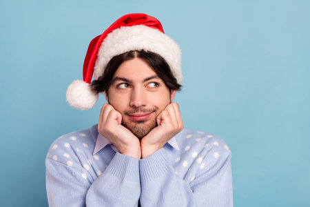 Photo of positive dreamy happy man look empty space imagine present christmas isolated on blue color backgroundの写真素材