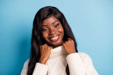 Portrait of charming cheerful dark skin lady hands touch collar beaming smile isolated on blue color...
