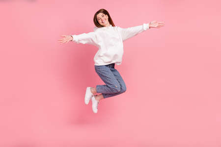 Full size photo of millennial lady jump hug wear hoodie jeans sneakers isolated on pink background