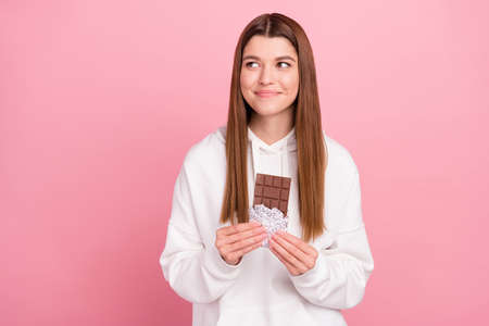 Photo of brown hairdo millennial lady hold chocolate look empty space wear hoodie isolated on pink...