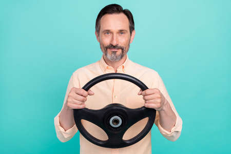 Portrait of mature good looking smiling taxi driver guy riding card hold steering wheel isolated on...