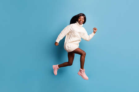 Full length photo of impressed funny dark skin lady wear white winter outfit jumping running...