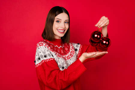Photo of sweet pretty young woman dressed print pullover holding new year decorations isolated red...