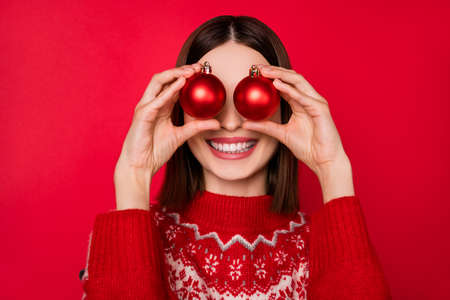 Photo of funny pretty young woman dressed print pullover smiling balls cover eyes isolated red color backgroundの写真素材