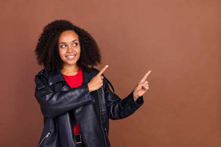Photo of attractive positive lady look indicate finger empty space isolated on brown color backgroundの写真素材